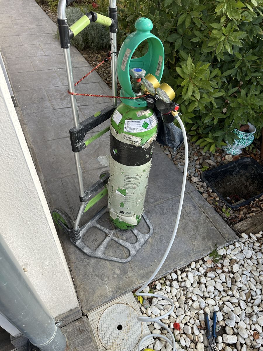 Botella de gas trazador en un carro junto a la vivienda